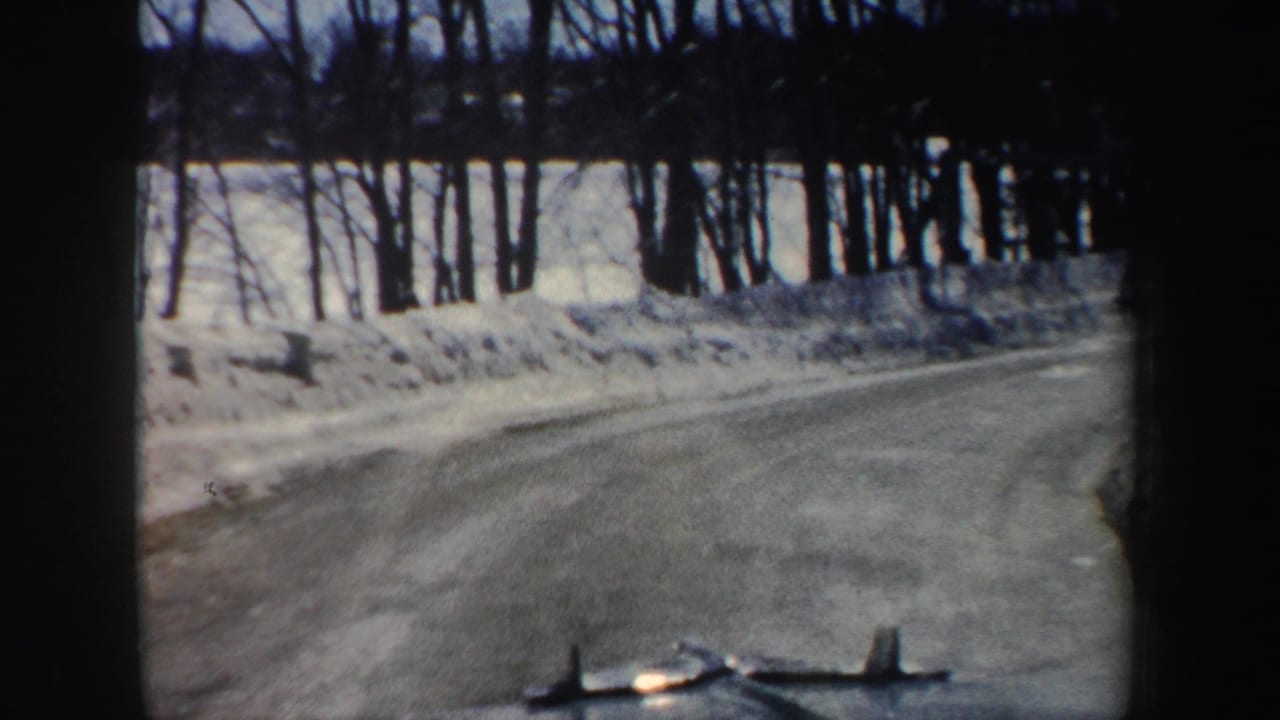 A rural New Hampshire road curves past snowbanks and winter trees in the final 1962 home-movie frame.