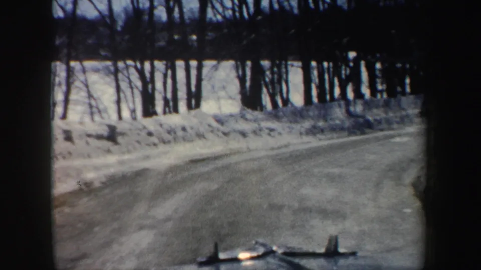 A rural New Hampshire road curves past snowbanks and winter trees in the final 1962 home-movie frame.