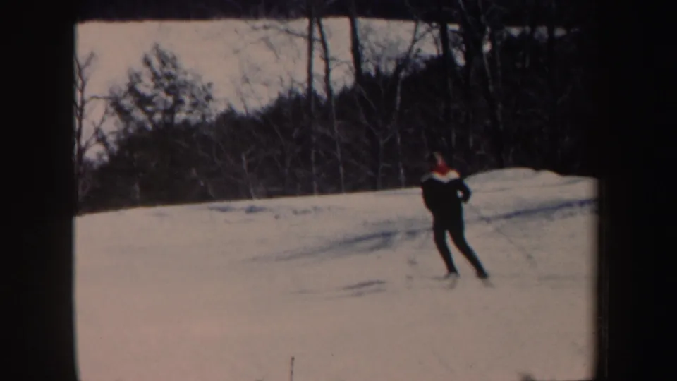 The skier continues downhill on a snowy New Hampshire slope, filmed from a casual 8mm home-movie viewpoint in 1962.