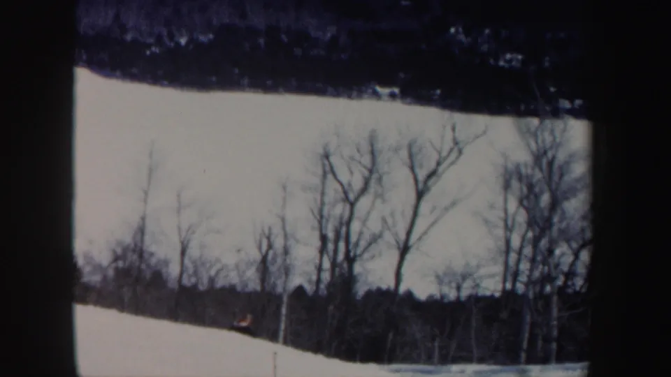 1962 New Hampshire 8mm frame showing a snow-covered hillside with leafless trees and dark film edges.