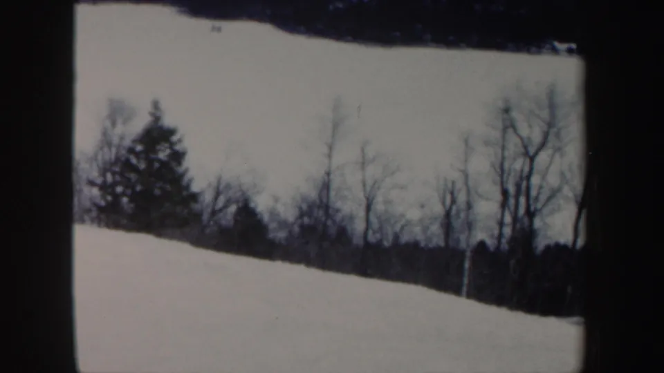 1962 New Hampshire 8mm frame showing a snowy wooded slope before the skier enters view.