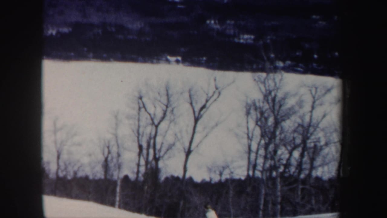 1962 New Hampshire 8mm frame showing a snow-covered slope with leafless trees under a pale winter sky.
