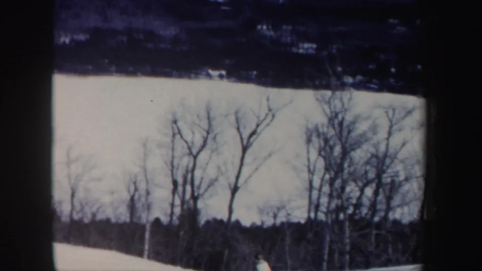 1962 New Hampshire 8mm frame showing a snow-covered slope with leafless trees under a pale winter sky.