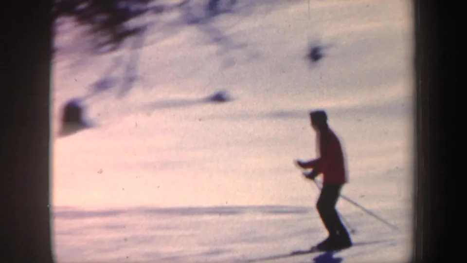 1962 New Hampshire home-movie frame of a red-jacketed skier moving across a snowy slope with ski poles.
