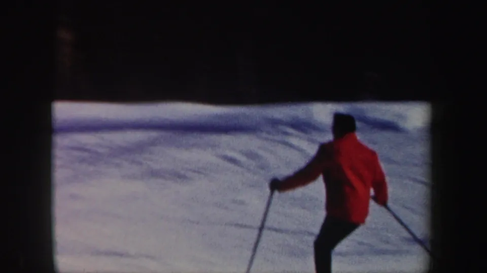 The skier continues across the snowy New Hampshire slope, filmed from a fixed 8mm home-movie viewpoint.