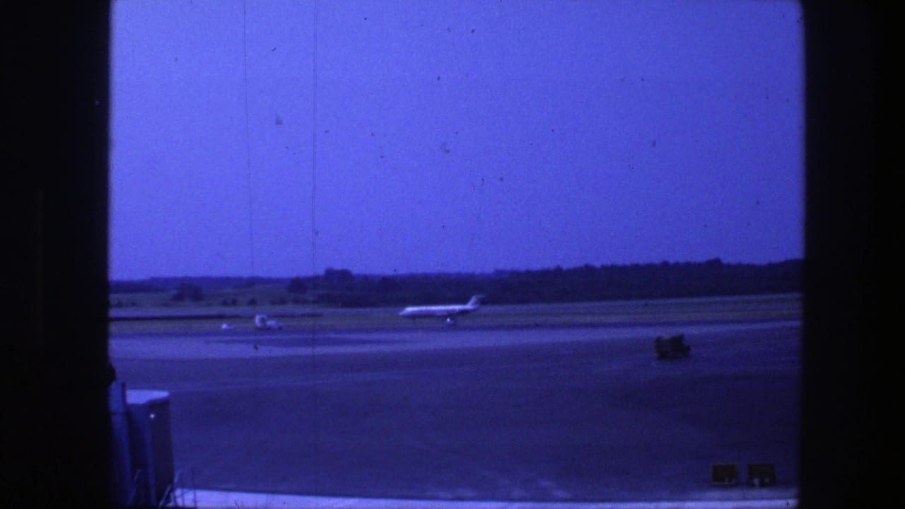 Jet aircraft taxiing on a runway beneath a blue sky with airport pavement in foreground.