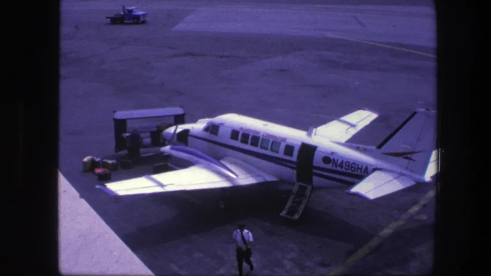 The home-movie view continues on the Copenhagen tarmac, with the small aircraft parked and a man walking in the foreground.