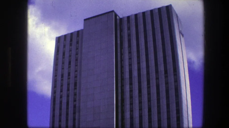 1975 Copenhagen 8mm frame with a closer low-angle view of the modern office tower and its repeated vertical facade pattern.