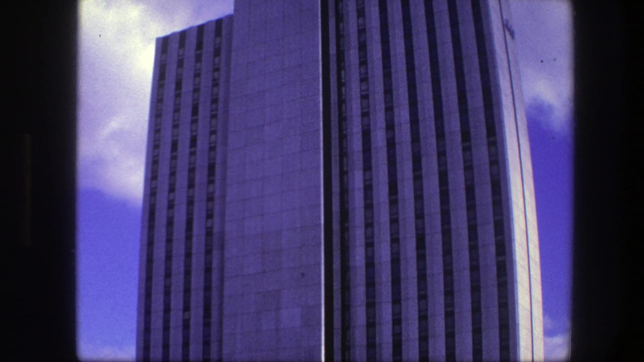 Tall concrete high-rise seen against blue sky through dark film-frame borders.
