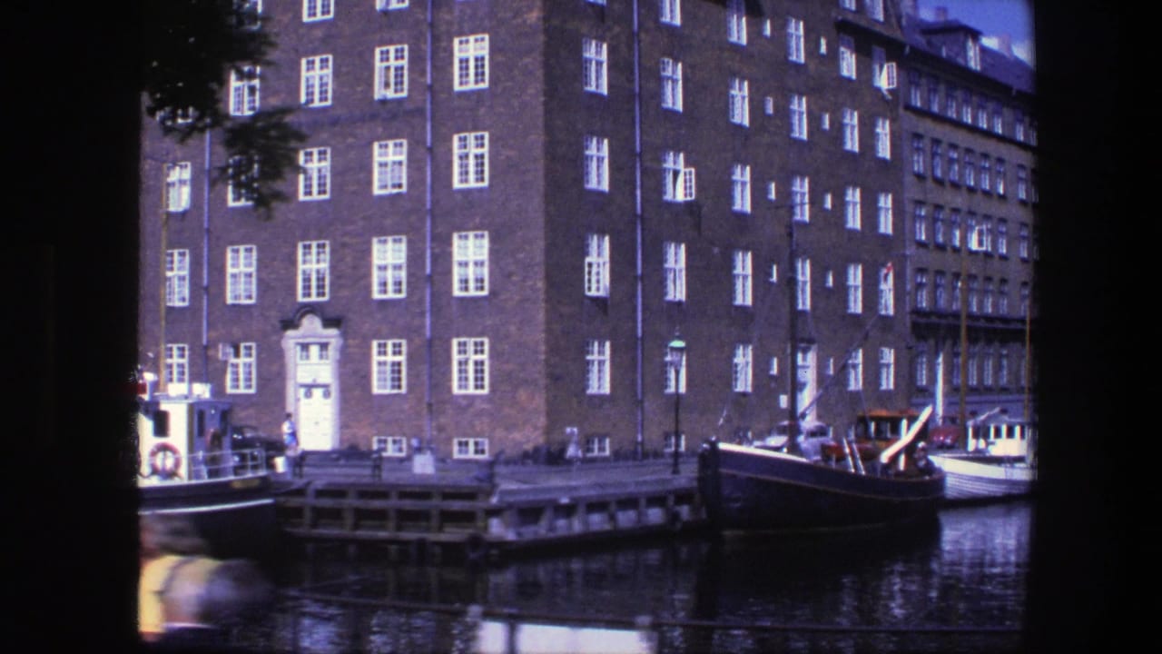 Canal-side brick buildings with boats moored along the dock and water reflections.