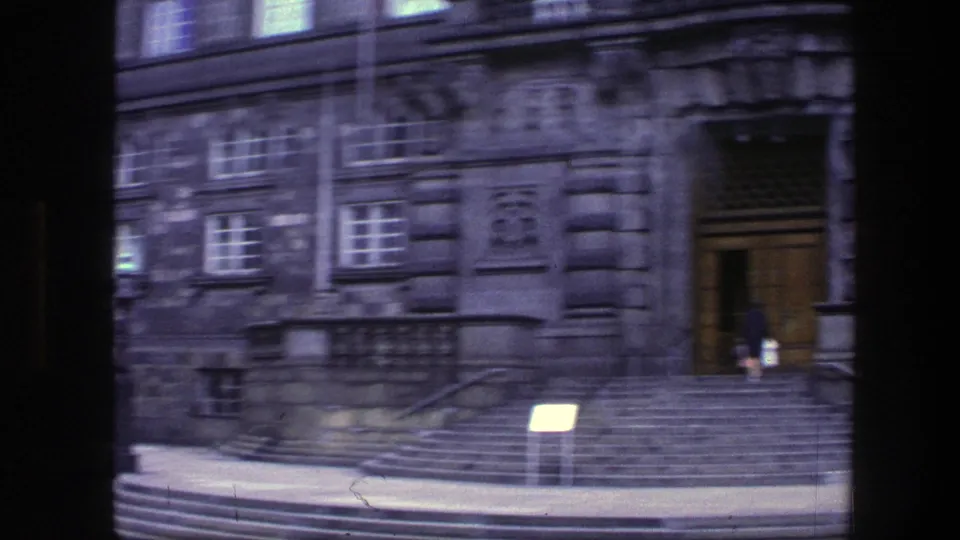 1975 Copenhagen view of a grand staircase, doorway, and small figure near the entrance of a stone building.