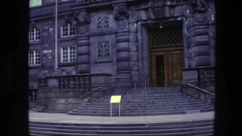 1975 Copenhagen frame centered on the carved stone entrance, wooden doors, broad steps, railings, and small signboard.