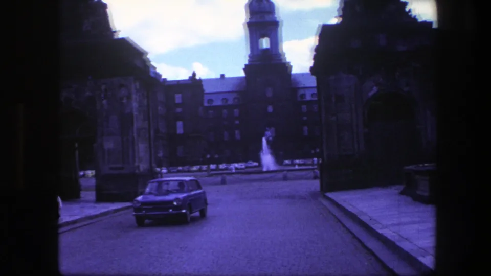 Copenhagen street view from 1975 showing a classic car passing near a fountain and tower-lined historic architecture.