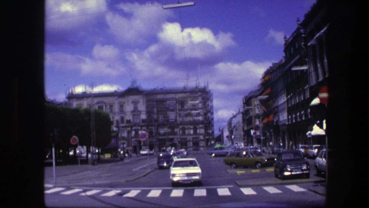 Wide Copenhagen street intersection with cars, crosswalks, buildings, and blue sky.