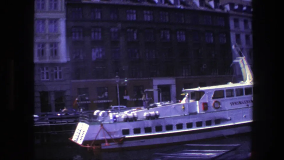 1975 Copenhagen harbor view showing the side of the SPRINGEREN boat, classic cars near the quay, and dark waterfront buildings beyond.