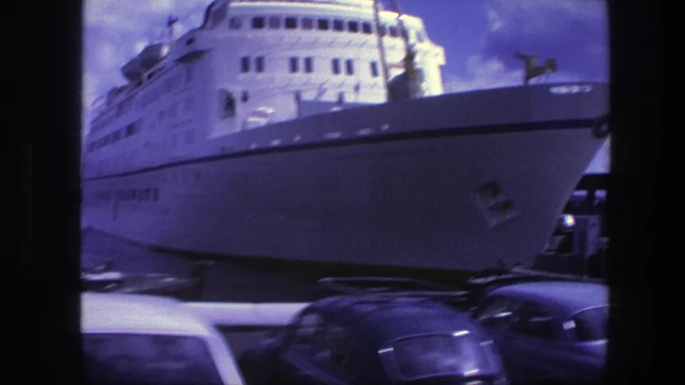 1975 Copenhagen harbor view of a large white passenger ship docked beyond parked cars, with the vessel filling much of the frame.