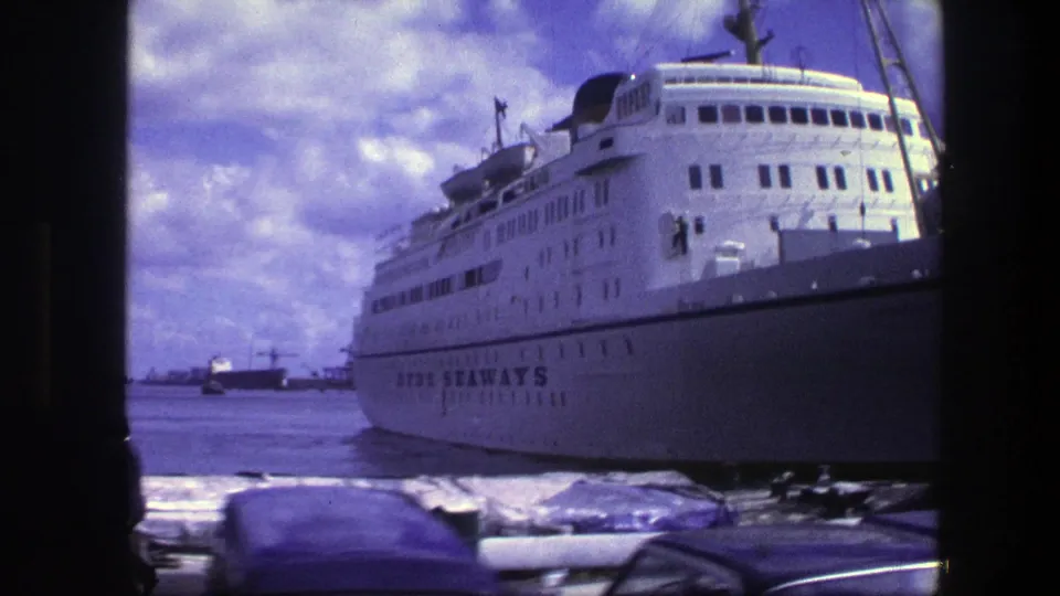 White SUN SEAWAYS vessel docked in Copenhagen, seen from a low waterfront angle with cars and harbor activity in front.