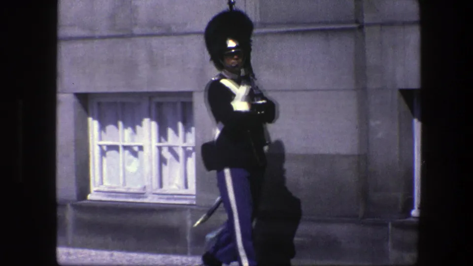 A Danish ceremonial guard appears to march along a Copenhagen building exterior in 1975 8mm footage.