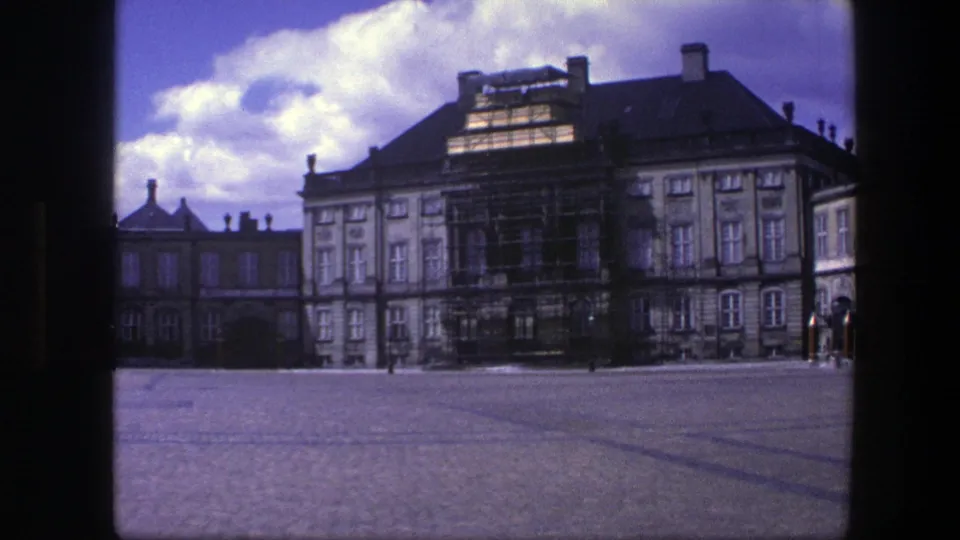 1975 Copenhagen view of Amalienborg Palace with scaffolding on the facade under a bright cloudy sky.