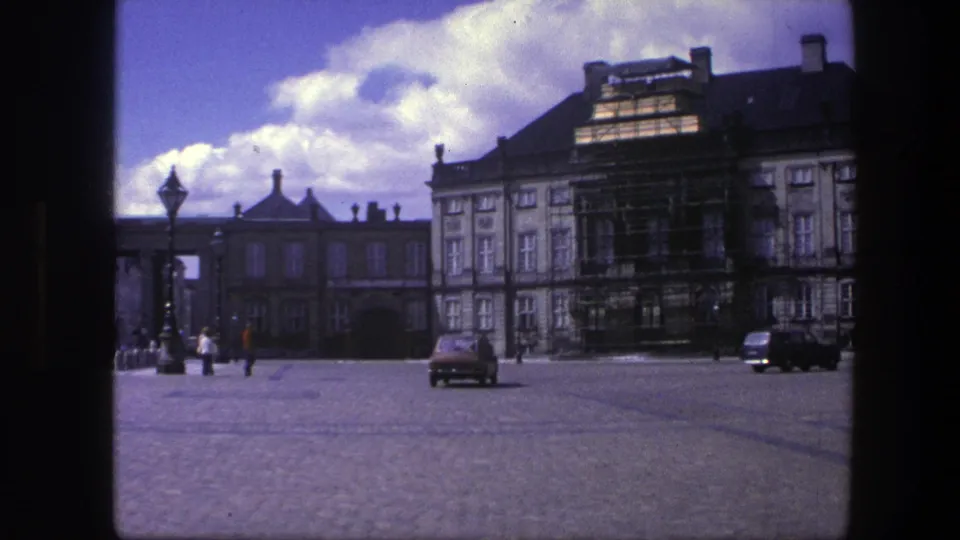 1975 Copenhagen view of cars and pedestrians in Amalienborg Palace courtyard with facade scaffolding visible.