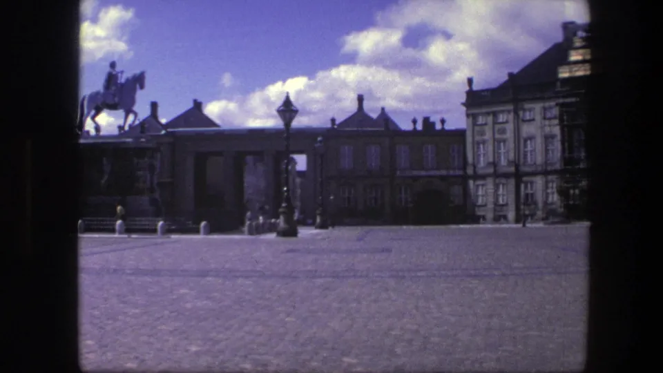 1975 Copenhagen 8mm view with the equestrian statue more visible beside the palace square and small pedestrians near the gateway.