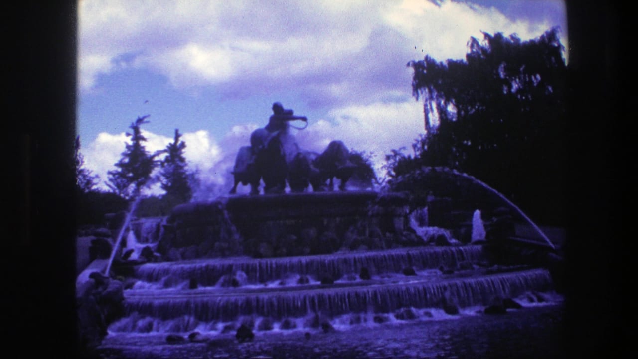 Cascading public fountain with water jets, trees, clouds, and an equestrian statue on top.