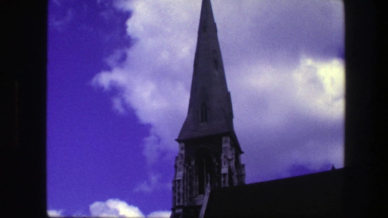 Sharp church steeple rising above a dark roofline against blue-purple sky and clouds.