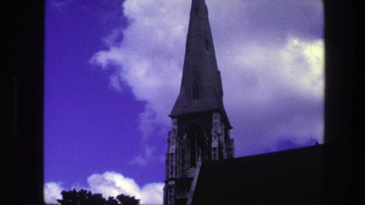 Church spire and roof edge framed beside clouds with dark film border at the side.