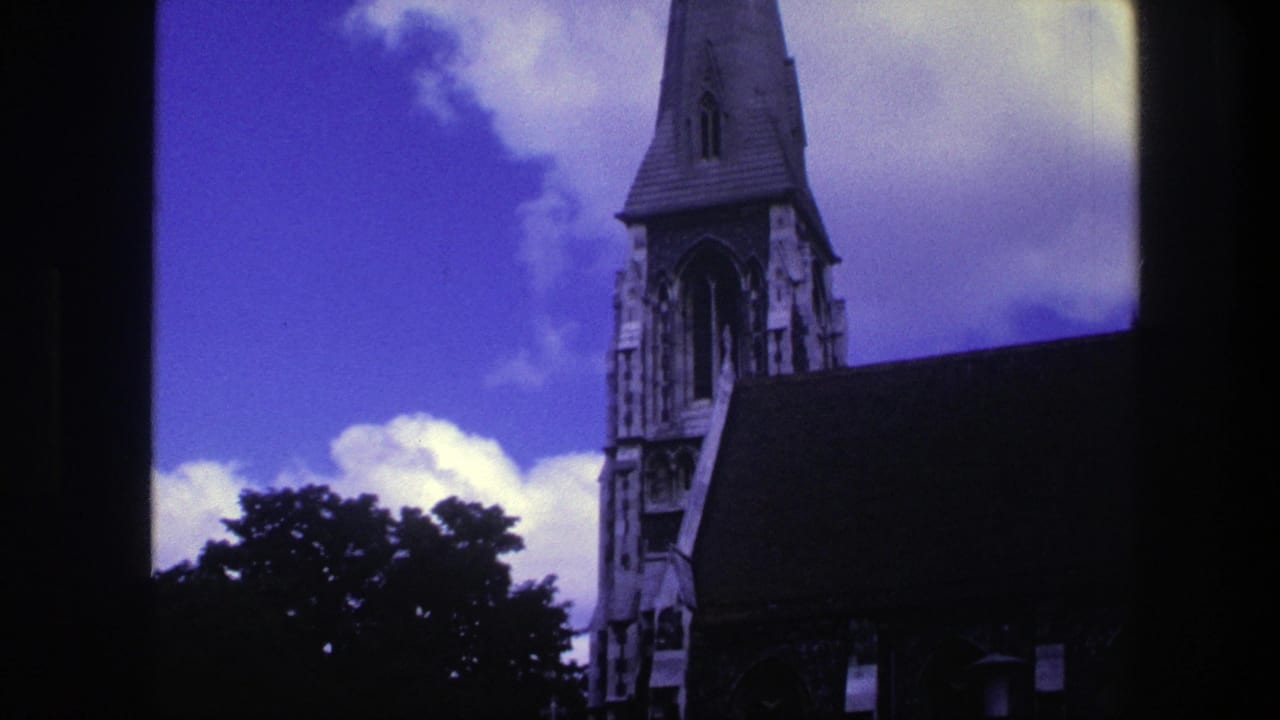 Tall church steeple and roof partly framed by dark vertical borders under a blue sky.