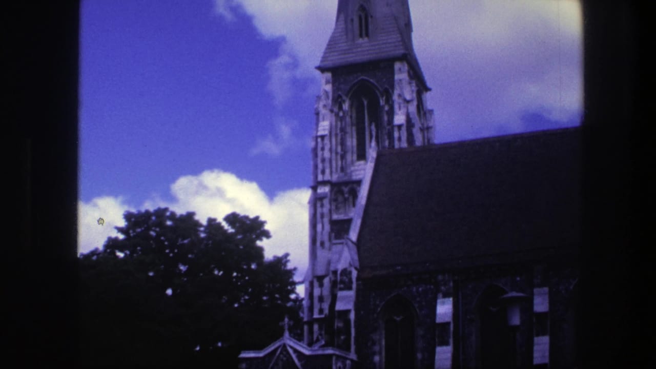 Church steeple, roof, trees, and dark window-like framing against a bright sky.