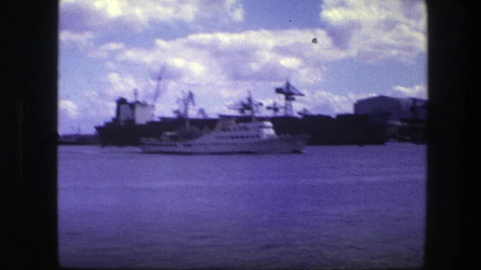 Soft 8mm frame of the Copenhagen harbor, with a white ship near cranes and dark port structures.