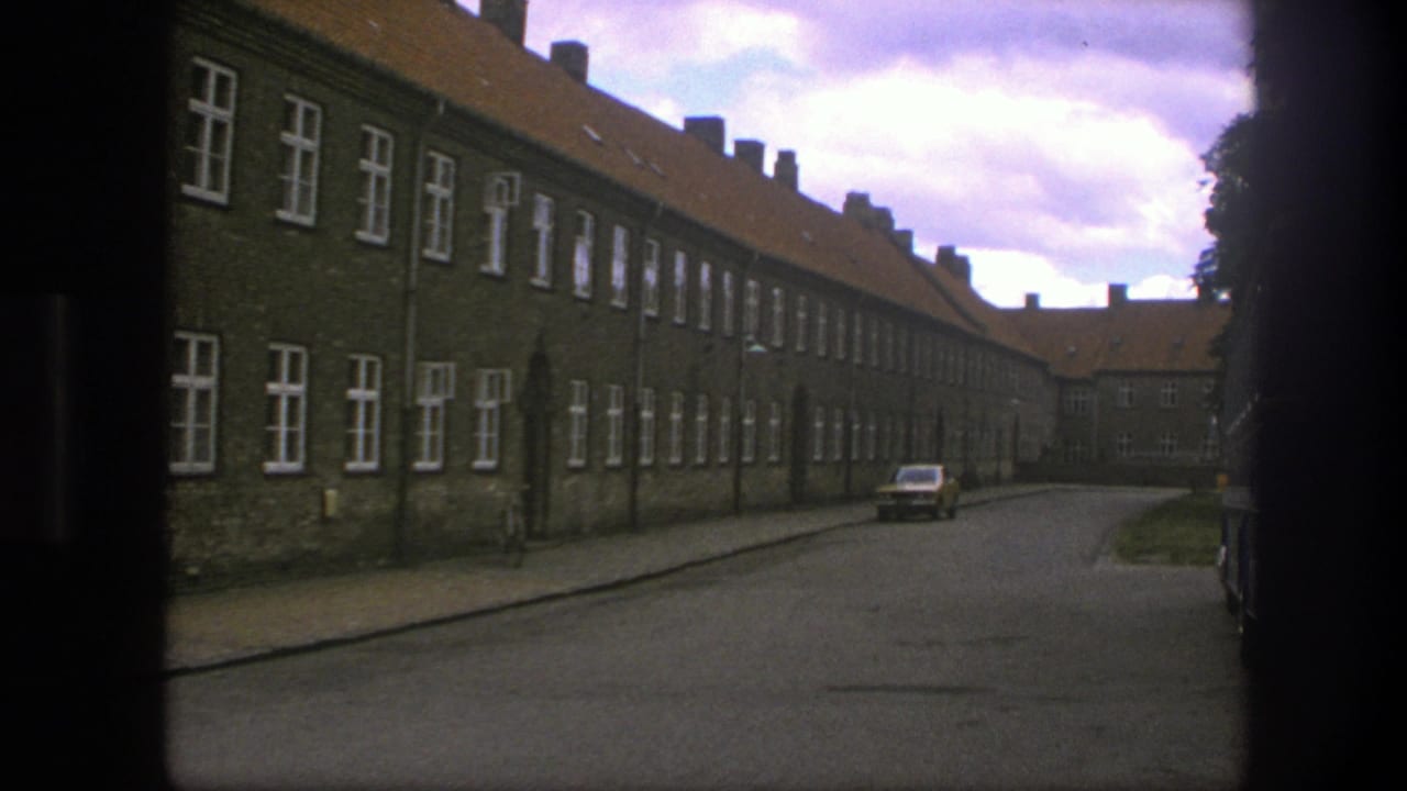 Quiet street lined with long brick buildings and a small parked car in the distance.