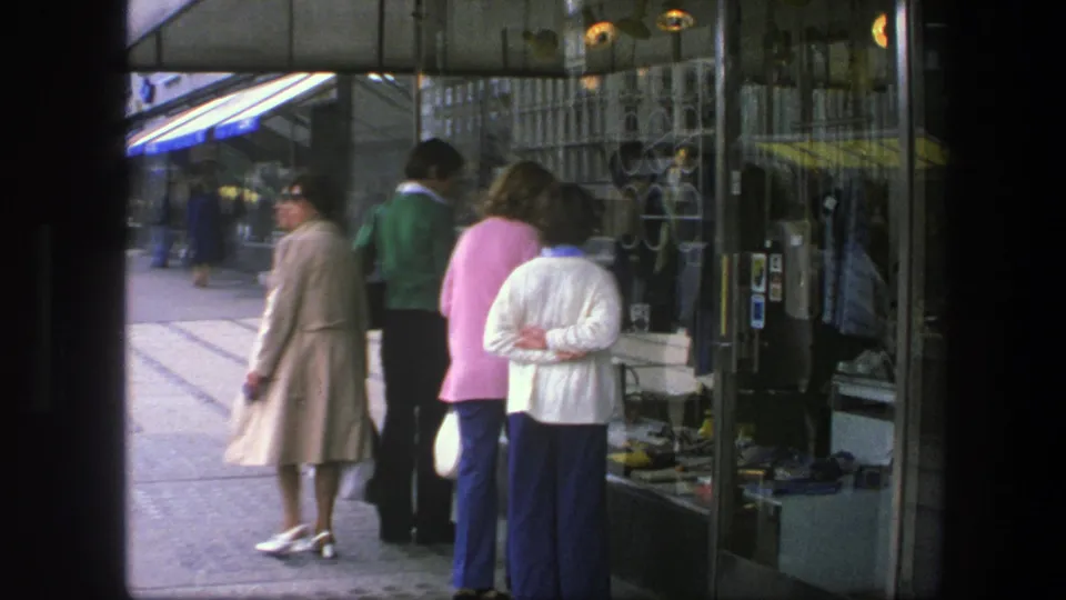 1975 Copenhagen sidewalk scene with adults window shopping beside glass storefronts, reflections, and merchandise displays.