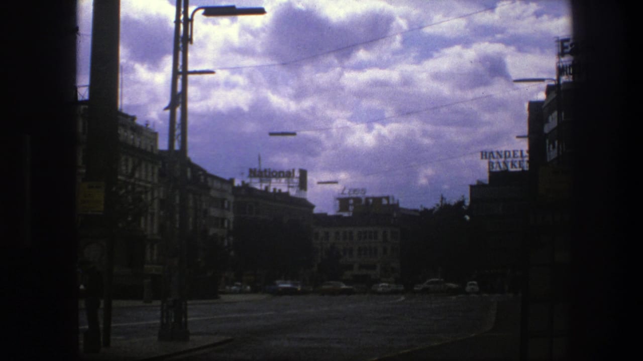 Urban street with heavy clouds, lamp posts, distant cars, and National and Handelsbanken rooftop signs.