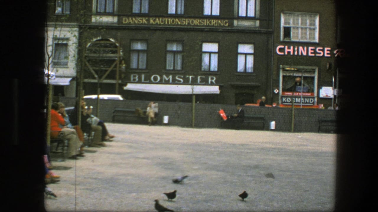 1975 Copenhagen square with pigeons on the pavement, benches, pedestrians, Blomster signage, and a Chinese restaurant facade.