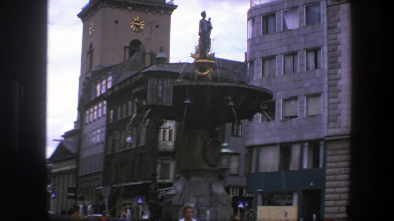 Stone fountain and clock tower in a Copenhagen square with pedestrians below.