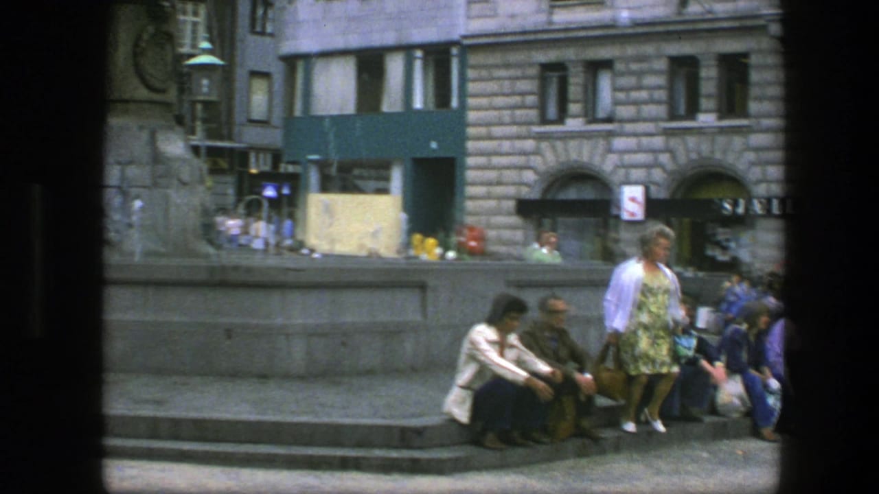 Copenhagen square view with seated pedestrians on stone fountain steps, a woman in patterned clothing, and stone-fronted buildings behind.