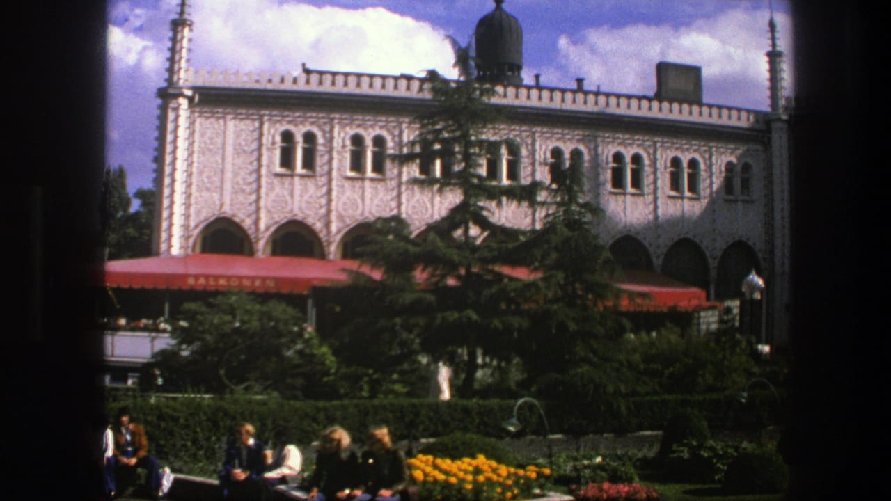 1975 Copenhagen 8mm frame showing people seated near flowers and hedges below an ornate building facade with red awnings.