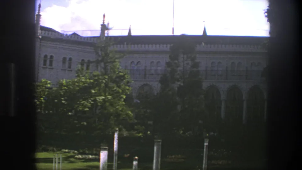 1975 Copenhagen 8mm frame showing a decorative facade with arched windows, partly blocked by dark window divisions and foreground trees.