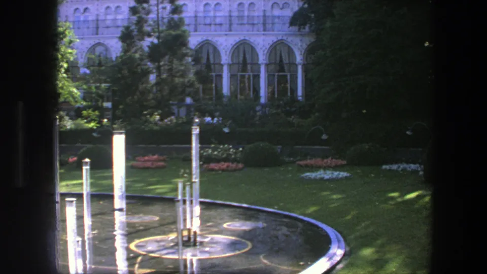 Late in the clip, the 1975 Copenhagen view shows the reflecting pool partly shaded, with columns, flowers, trees, and arched windows.