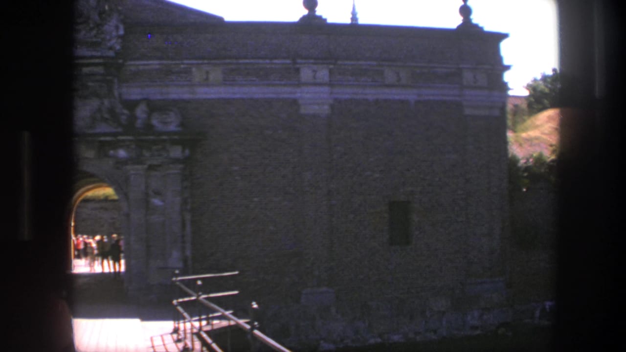 The Copenhagen fortress entrance remains centered as visitors appear as small silhouettes in the bright arched passage.