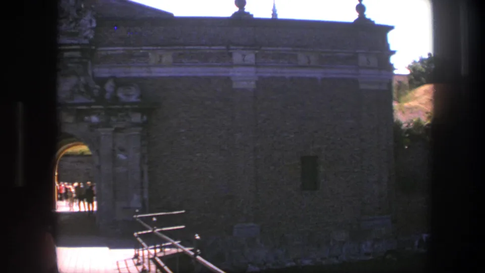 The Copenhagen fortress entrance remains centered as visitors appear as small silhouettes in the bright arched passage.