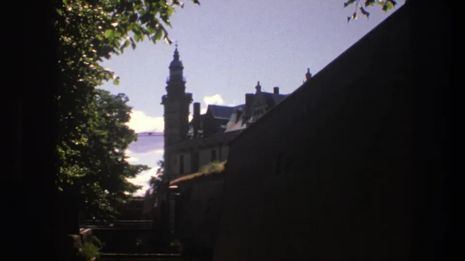 A 1975 Copenhagen castle exterior appears through foliage, with the right side held in deep shadow.