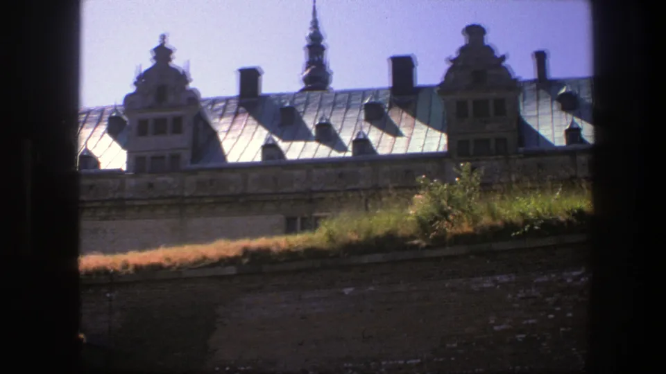 1975 Copenhagen 8mm still showing an ornate roof, chimneys, gables, grass, and brickwork under a clear sky.