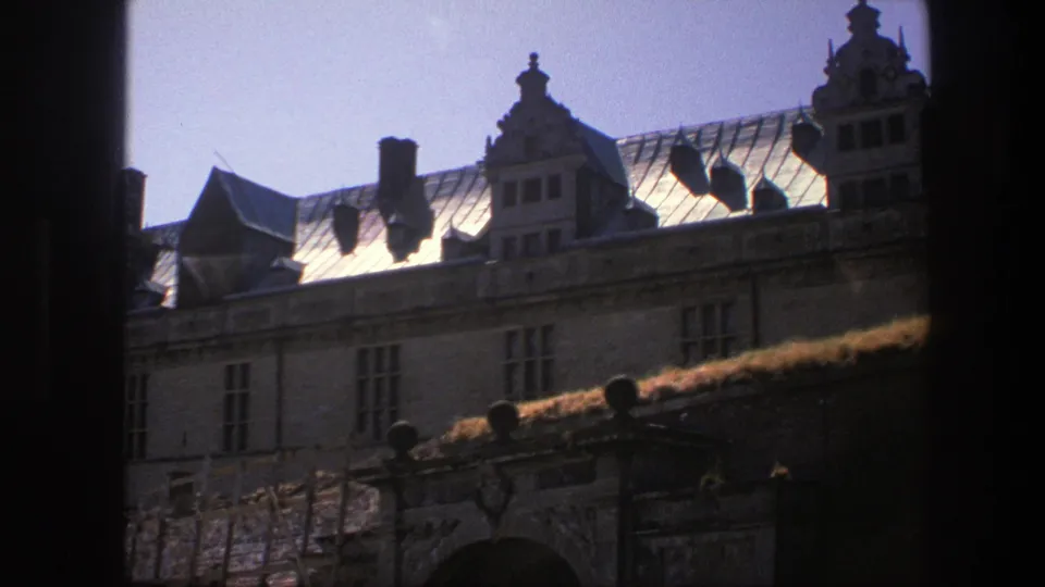 Copenhagen mansion exterior with reflective roof panels, chimneys, gables, and multi-paned windows on 8mm film.