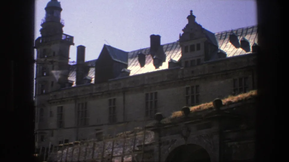 Copenhagen 8mm frame showing a historic mansion facade, roof gables, chimneys, and a tower-like edge at left.