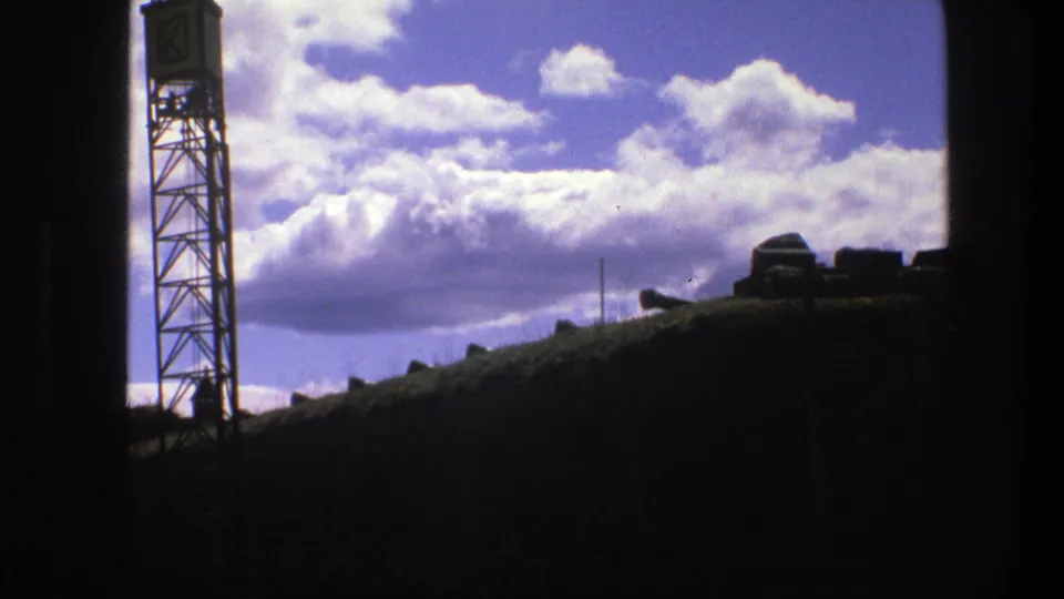 1975 Copenhagen frame showing the tower at left, dark skyline forms, and sunlit clouds across the sky.