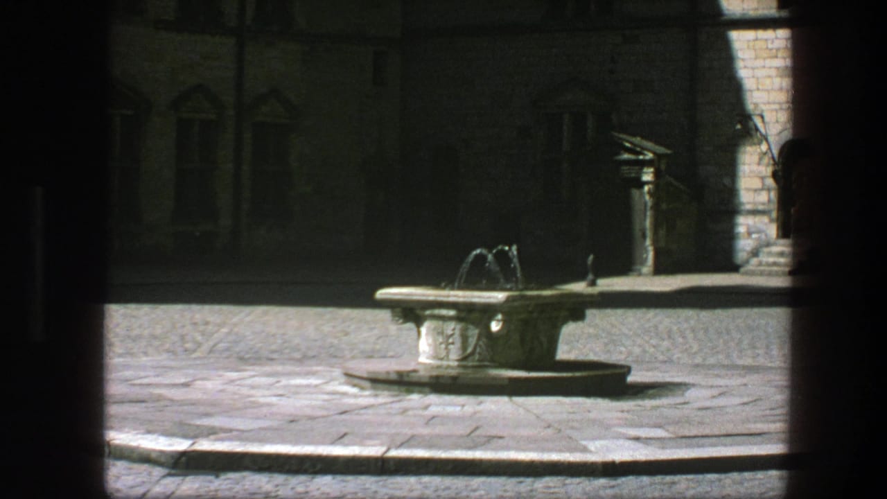 Stone fountain in a Copenhagen courtyard, with old masonry walls and windows visible beyond the shaded foreground.