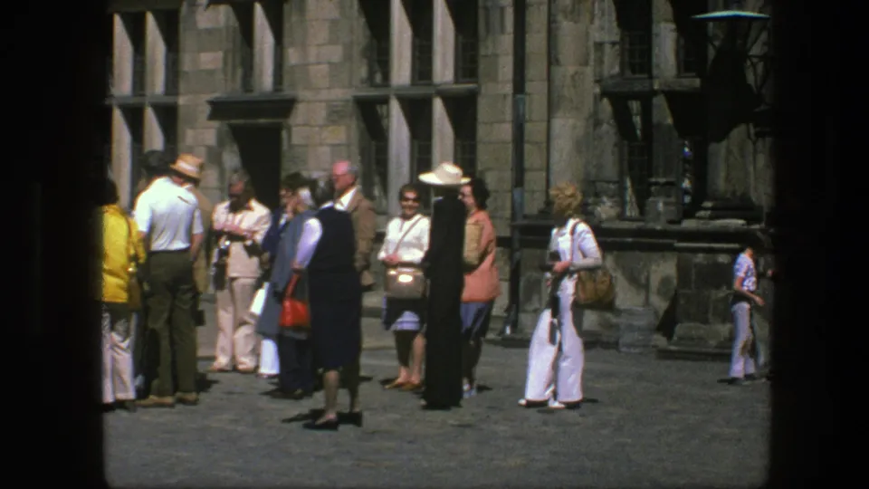 Copenhagen 1975 home-movie still showing tourists gathered by a stone building, with one visitor walking across the frame.