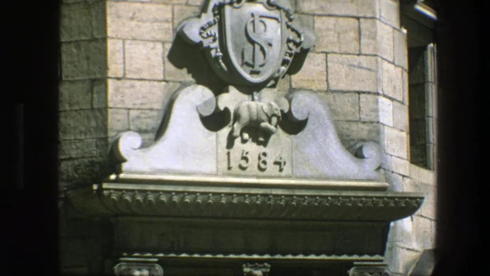 Final 1975 Copenhagen frame of an ornate stone doorway top, with a shield-like emblem, elephant carving, and 1584 date.